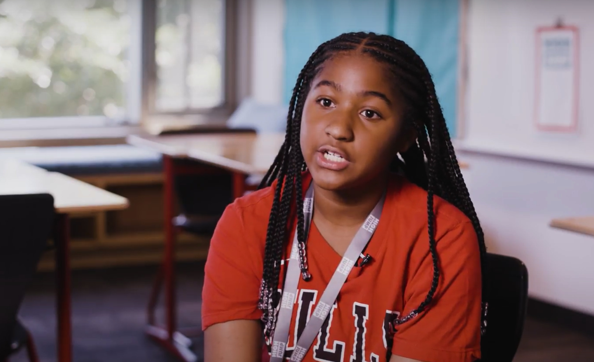 CeCe sits at a desk while a High Jump TA speaks to her