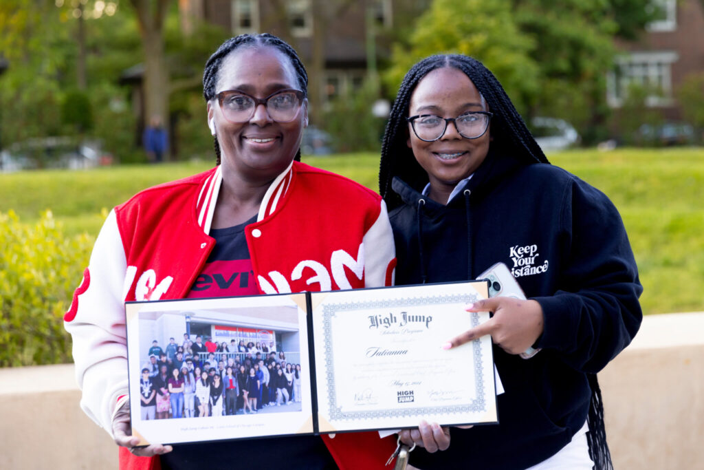 A high jump student stands with her mother showcasing her diploma